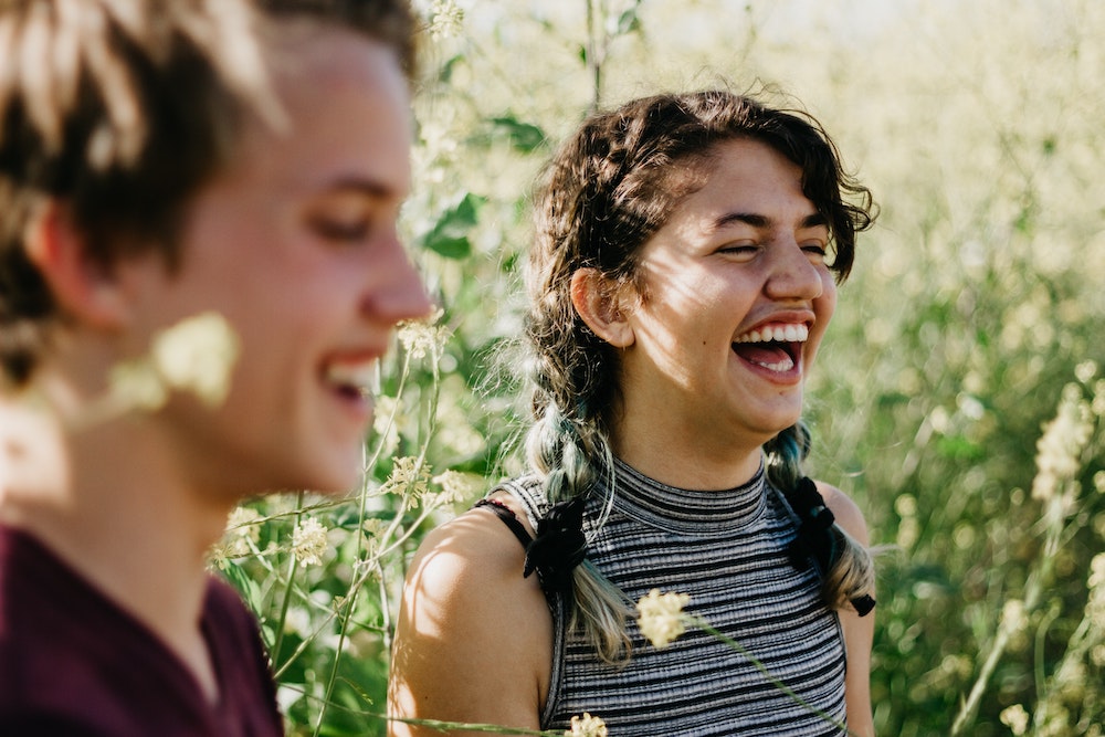 Young woman and man laughing in a field